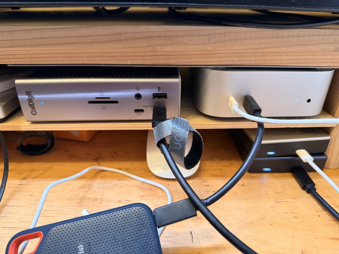 デスクシェルフの下に置いたMac miniとCalDigit TS4。外付けSSDやケーブルがつながっている