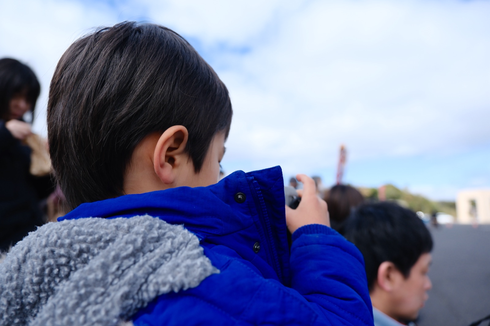 青い上着でPENTAX WG-1000を構える子どもの後ろ姿