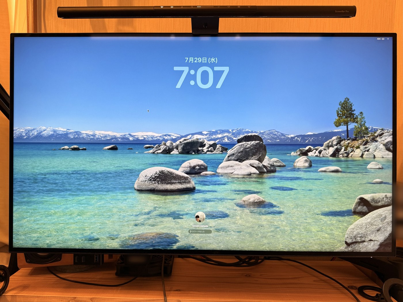 エルゴトロンのアームに載せた32インチ4Kモニター。画面には湖の写真が映り、上にはBenQのScreenBar Proが付いている