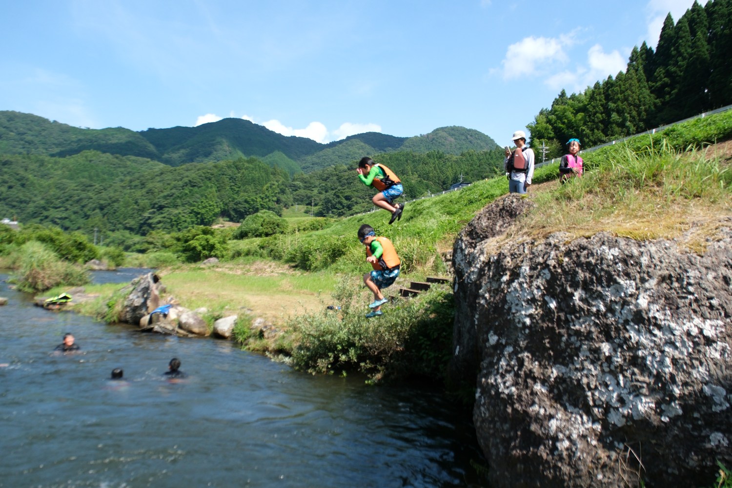 兄弟ふたりが同時に岩から川へ飛び込む瞬間