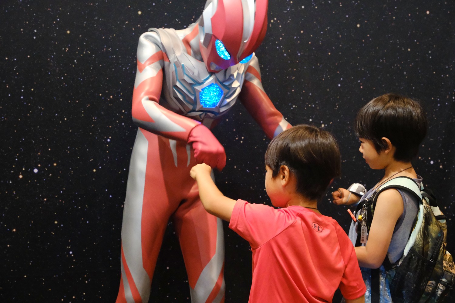 ウルトラマンと拳を合わせる子どもたち