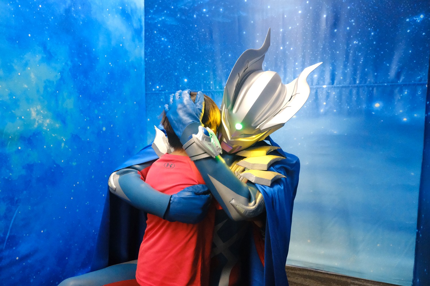 ウルトラマンに抱きしめられている子どもの後ろ姿