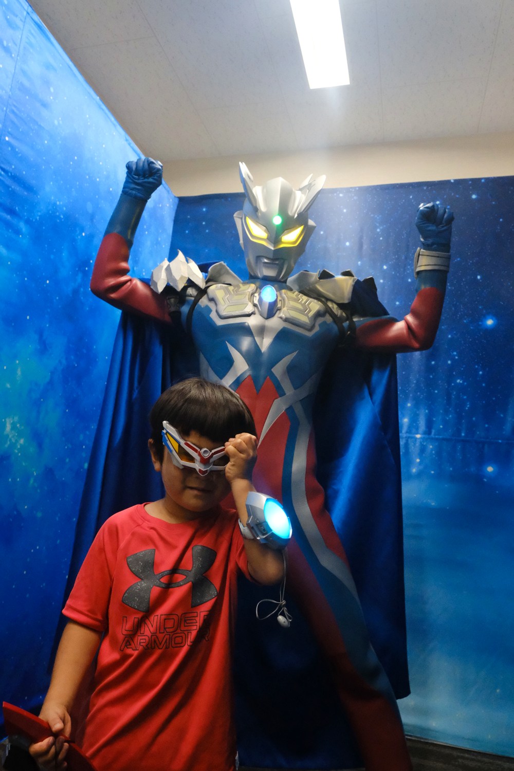 ウルトラマンと並んでポーズをとる子ども