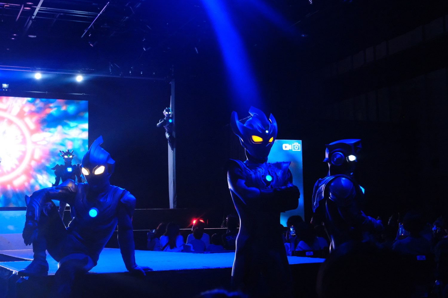 ウルトラマンショーのステージ。青い照明の中に並ぶヒーローたち