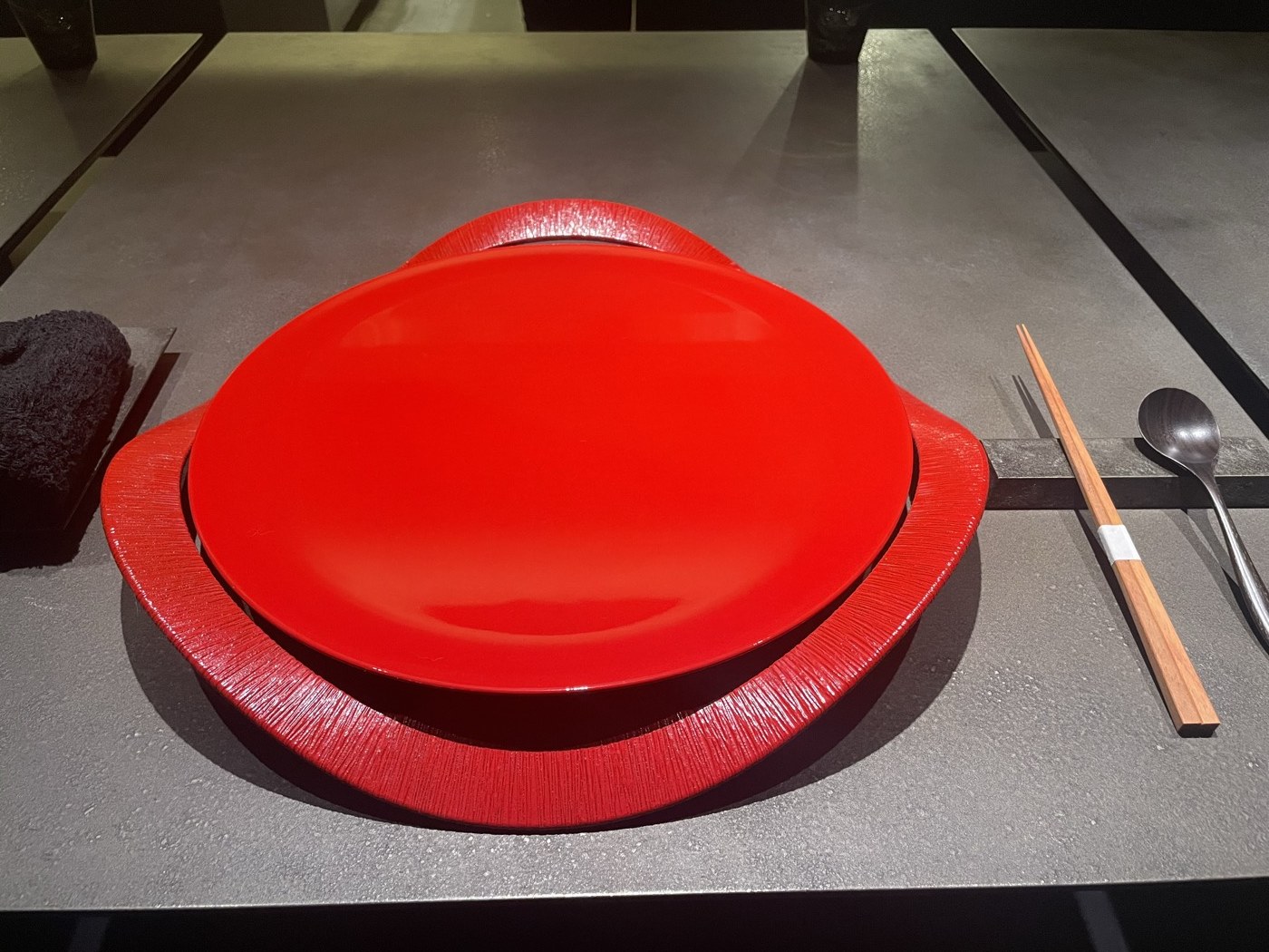 赤い漆の器と箸が置かれたカウンターの席