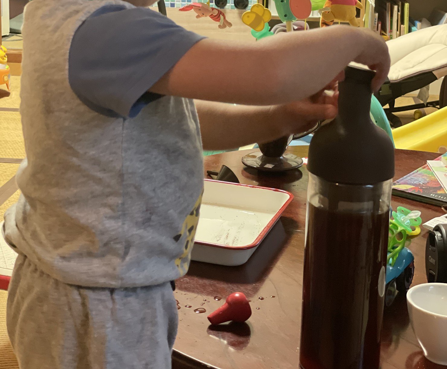 幼い子どもが、水出しコーヒーのボトルのふたに手をかけている