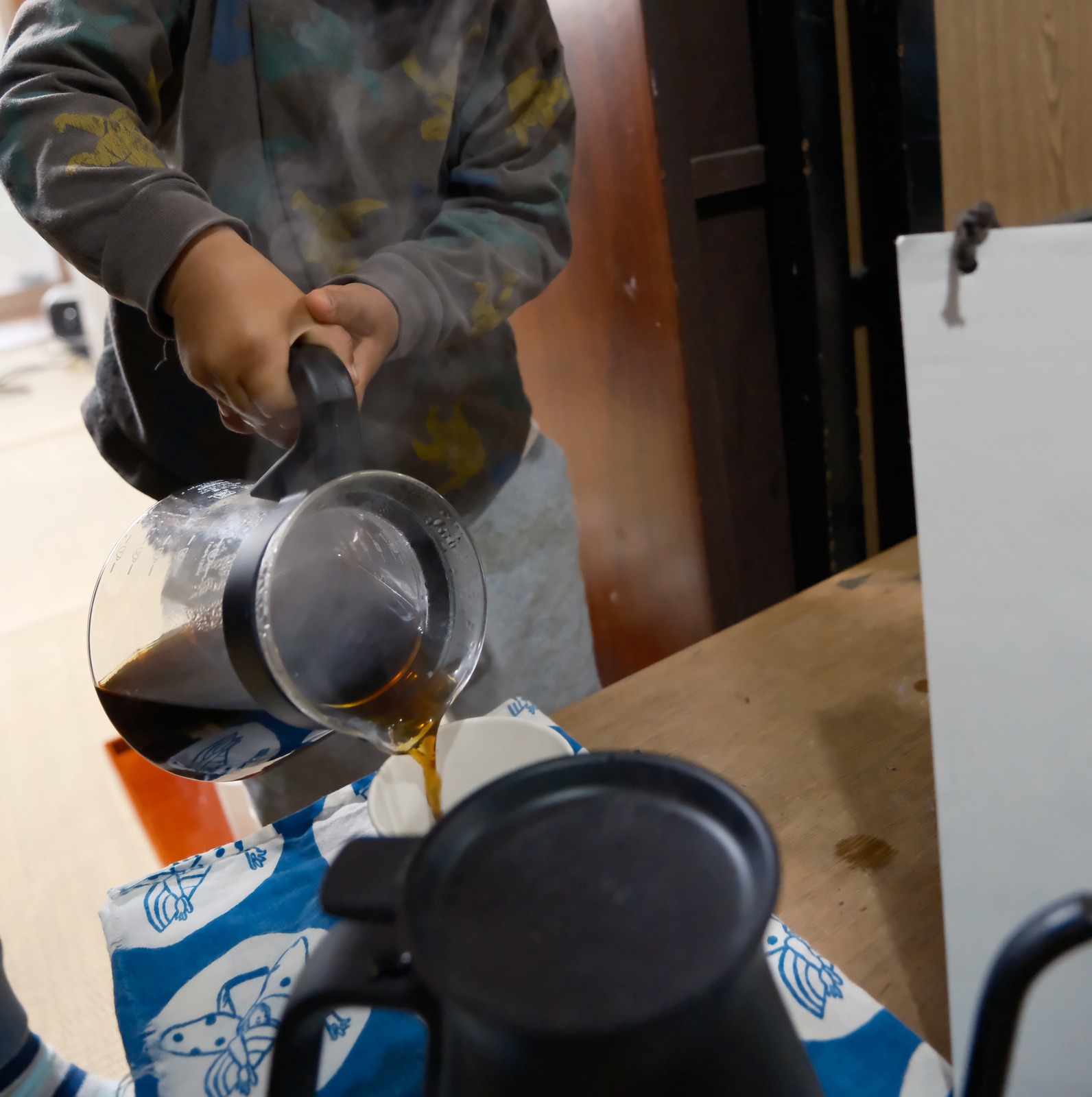サーバーから紙コップへ注がれるコーヒーと、立ちのぼる湯気