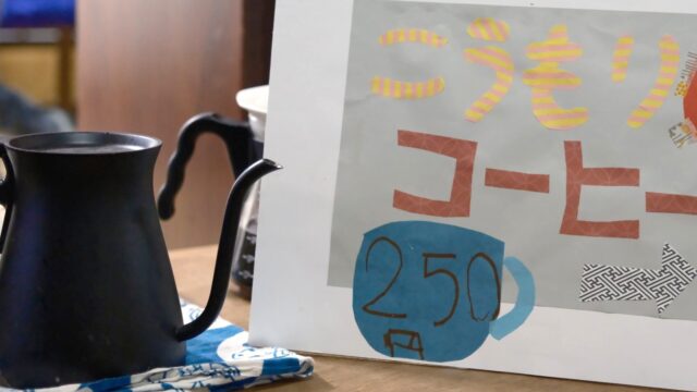 こうもりコーヒーの手作りの看板と、黒いコーヒーポット。一杯250円