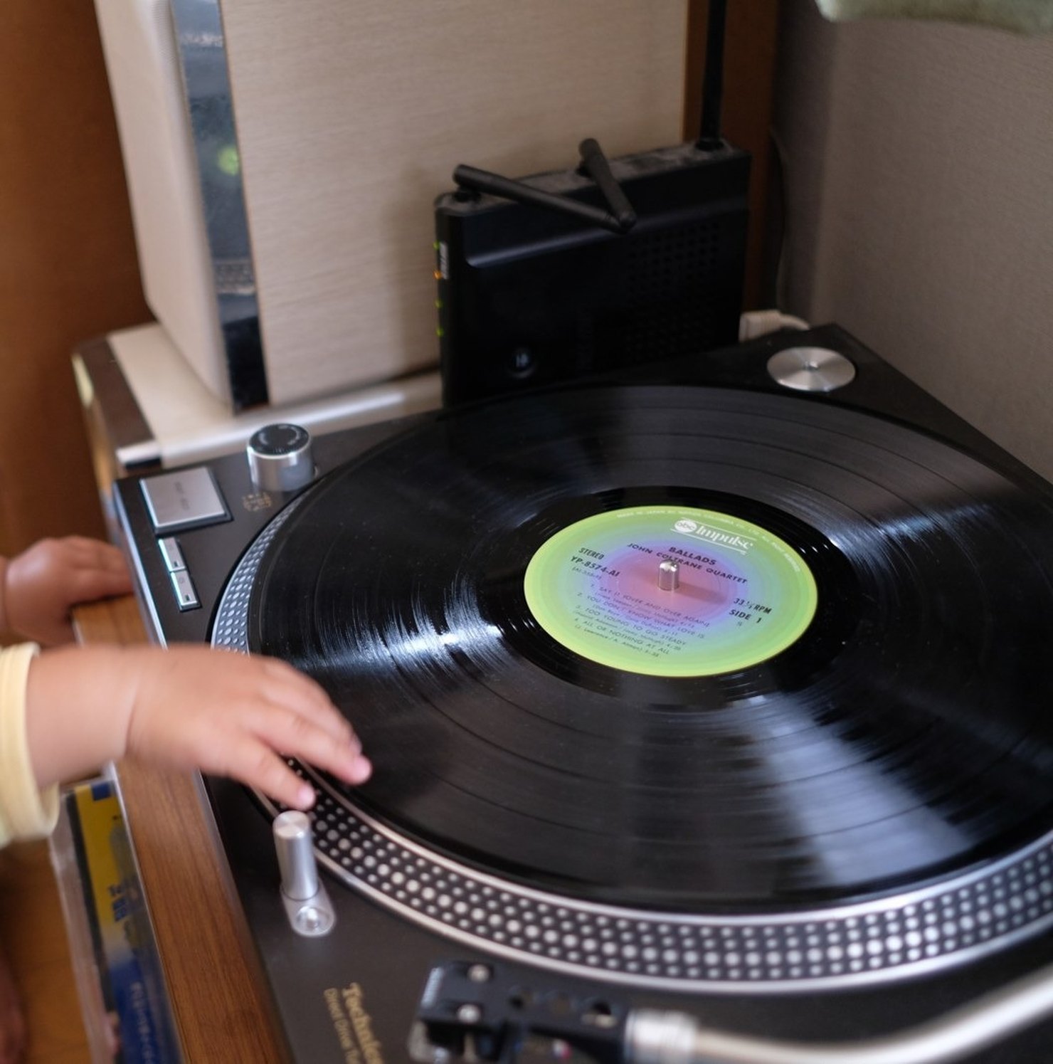 Technics SL-1200MK6に載ったジョン・コルトレーン・カルテット『バラード』のレコードに、小さな子どもの手が伸びているところ