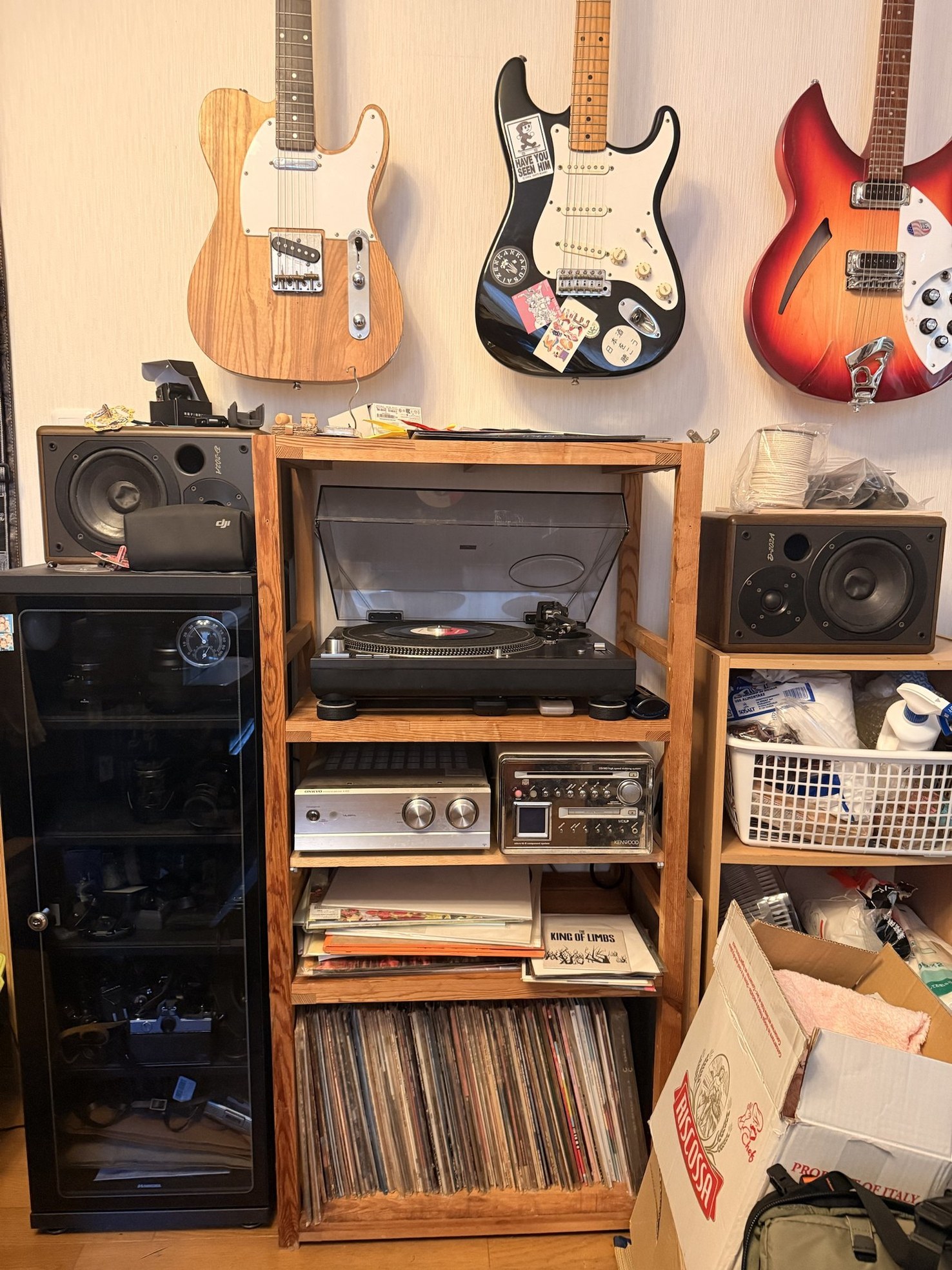 木のラックに並んだ、いまの機材。上段にTechnics SL-1200MK6、中段にONKYO A-933とKENWOODのMDコンポ、下段にレコードの棚。両脇にONKYO D-202Aのスピーカー、壁にはギターが三本