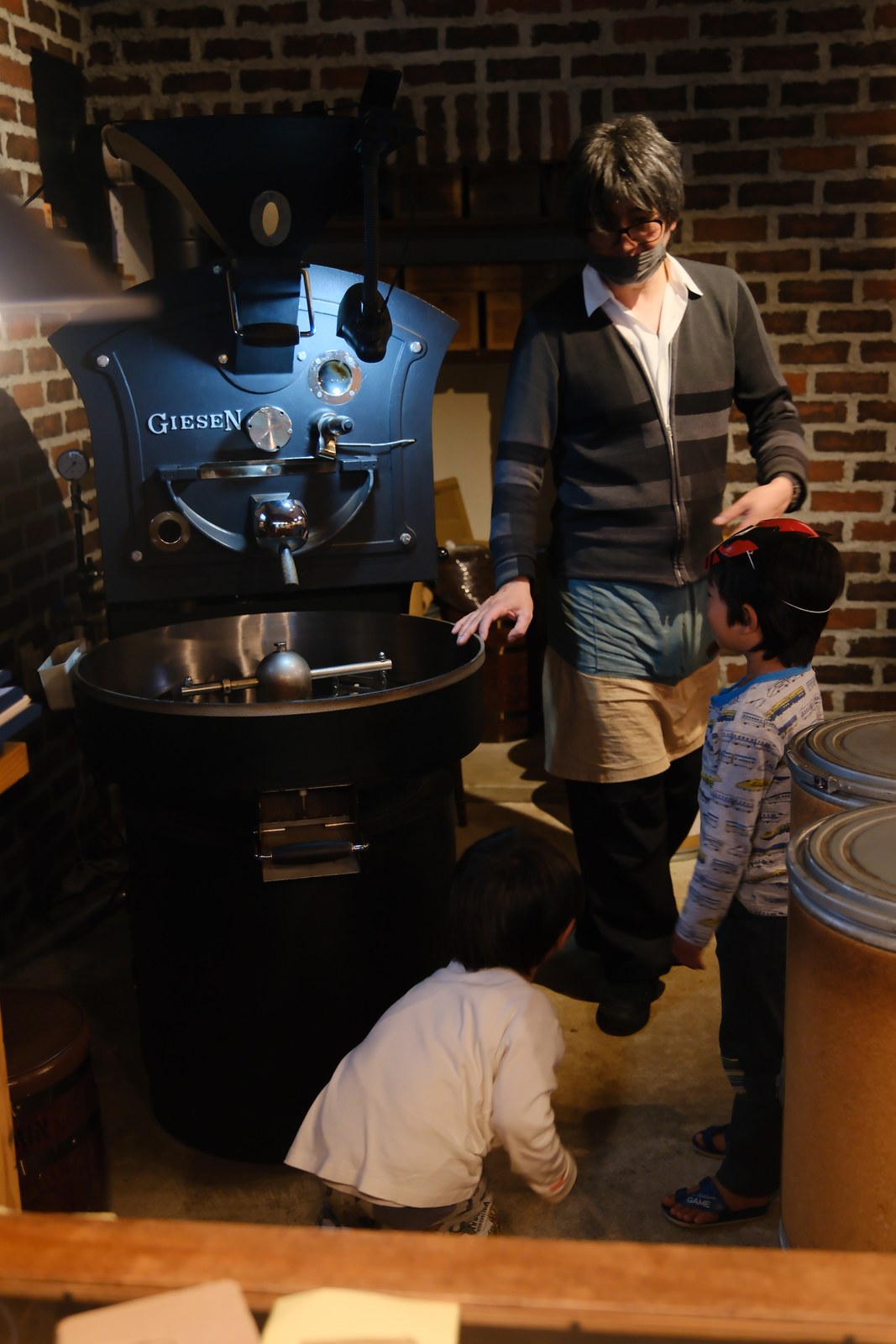 ギーセンの焙煎機のそばに立つ飯島さんと、子どもたち