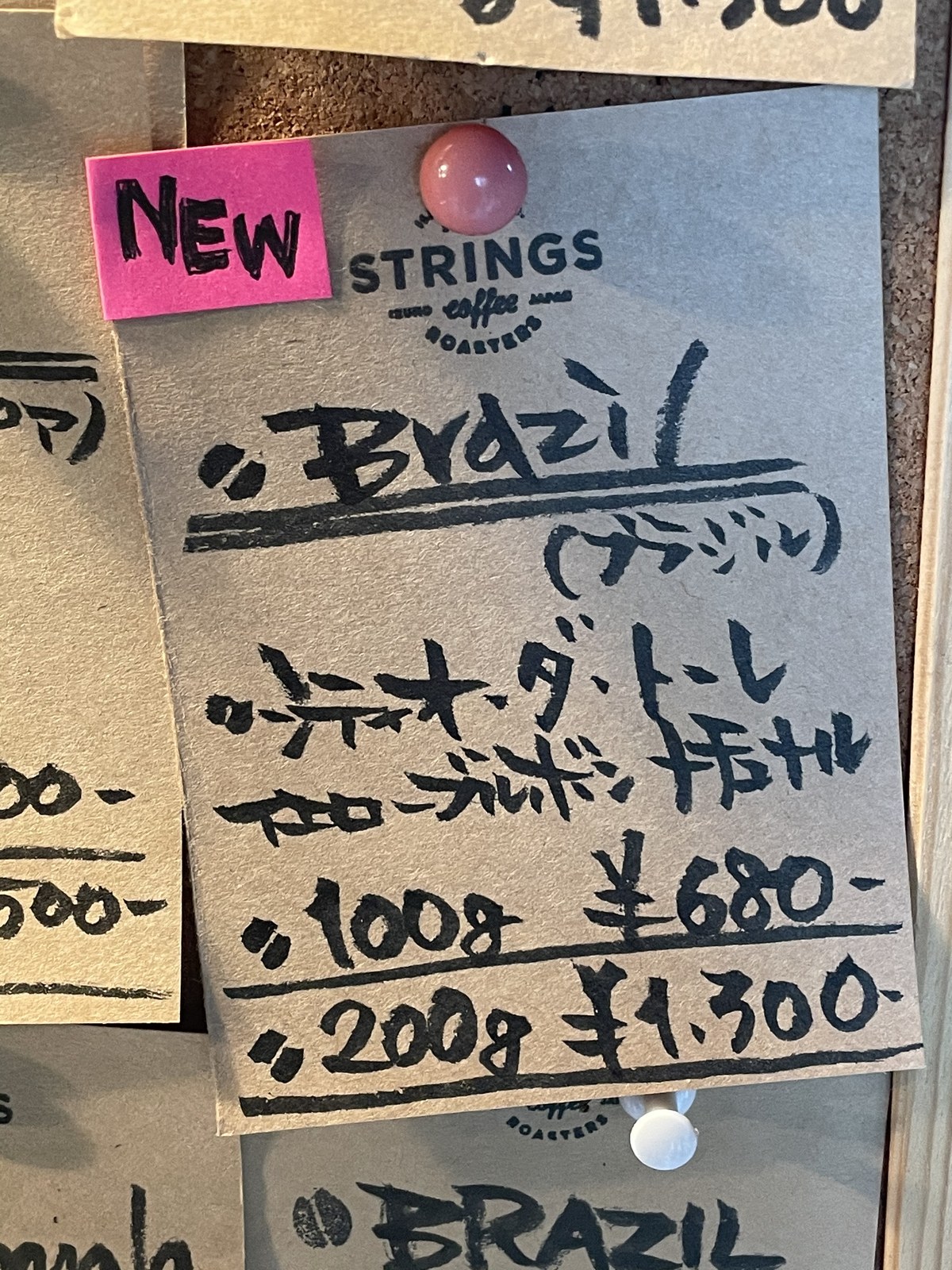店の手書きの値札。Brazil、100g 680円、200g 1,300円