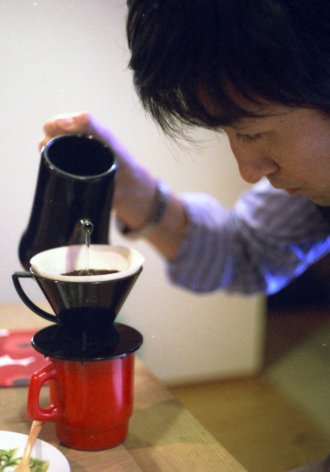 真剣な横顔でポットからコーヒーを注ぐフィルム写真