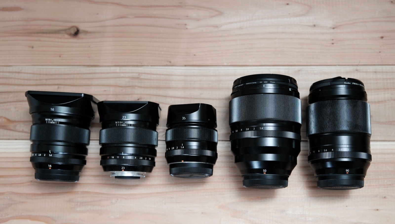 机に並べた FUJIFILM XF の単焦点レンズ5本。左から16mm、23mm、35mm、50mm、90mm