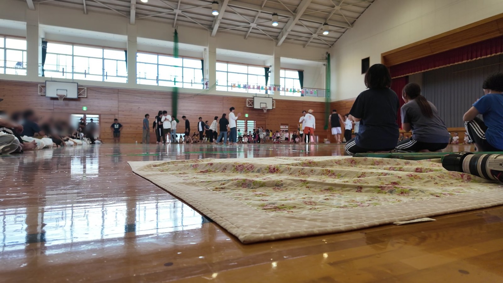 保育園の運動会の体育館。床のシートに置いたカメラの Osmo Pocket 3 で撮った1コマ。床の高さからでも水平に写っている