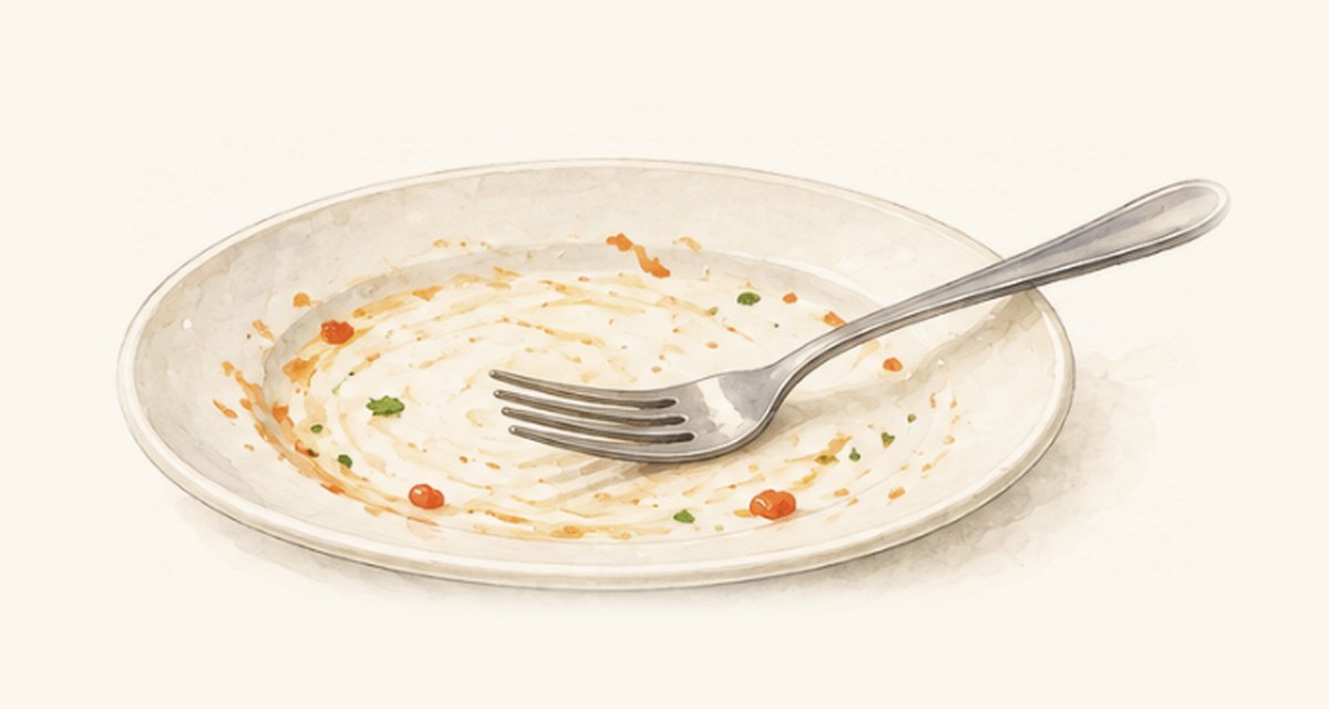 食べ終わってソースがほとんど残っていない白い皿とフォーク