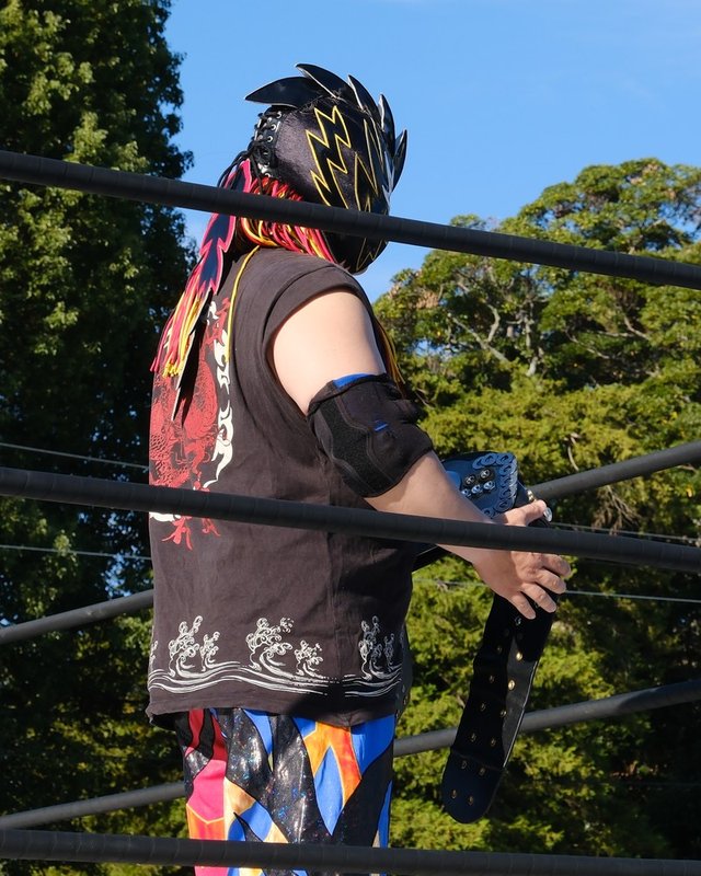 KYOHEI選手の後ろ姿。黒いマスクに黒いTシャツ。ベルトを持つ