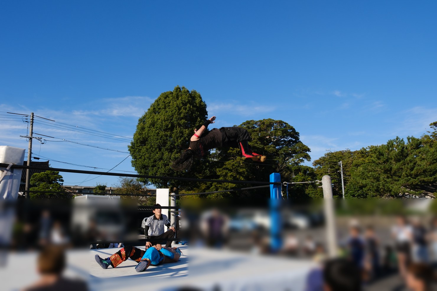 コーナーポストから飛んで、空中で回転する野津朋也選手。リングには相手の選手と審判