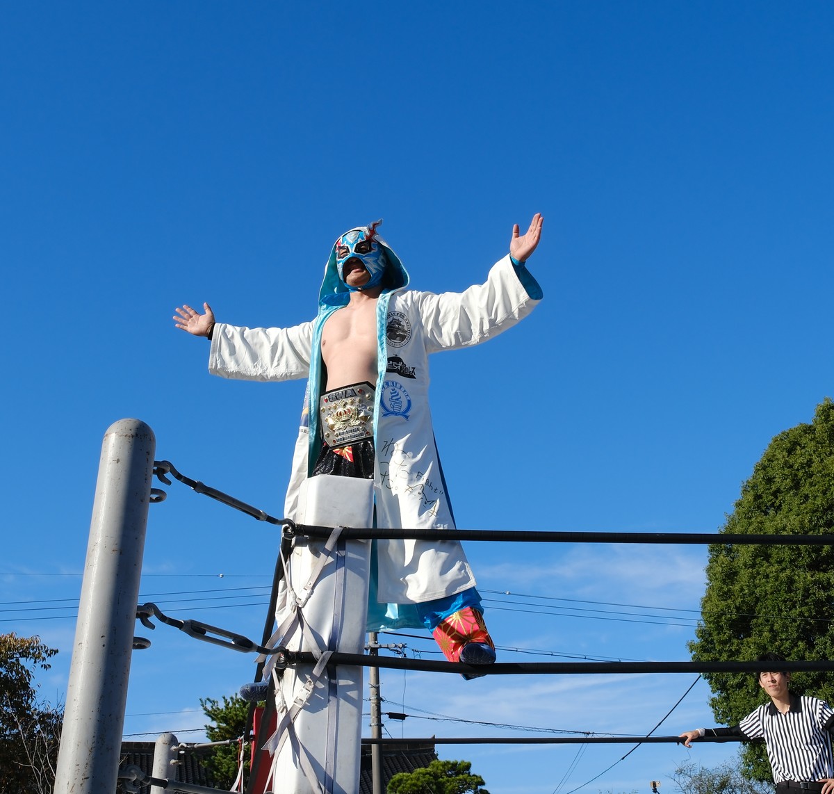 白いガウンで、コーナーポストの上で両手を広げるスサノオKID選手